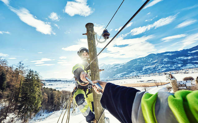 Netzelektriker:innen arbeiten im Team auf Strommasten